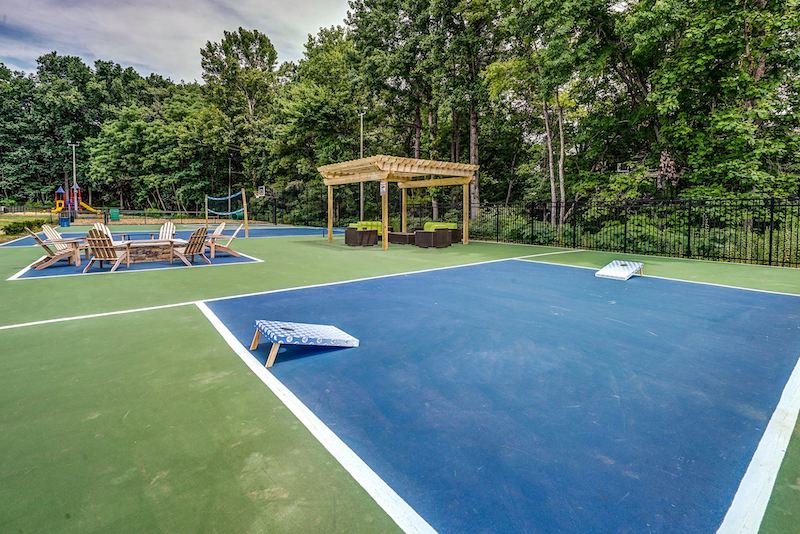 Large green and blue court with corn hole, a fire pit, and couches