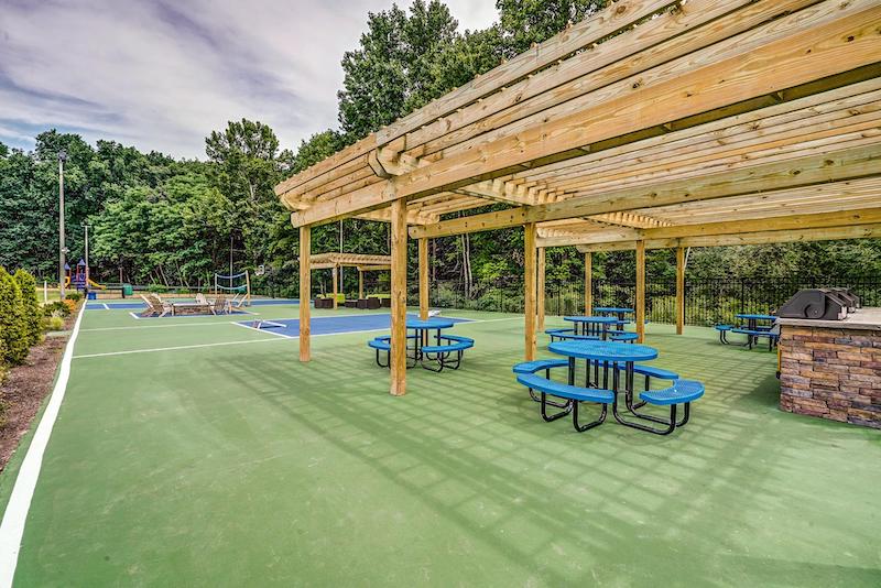 Gazebo with grills and patio tables, with a multi-sport court in the background
