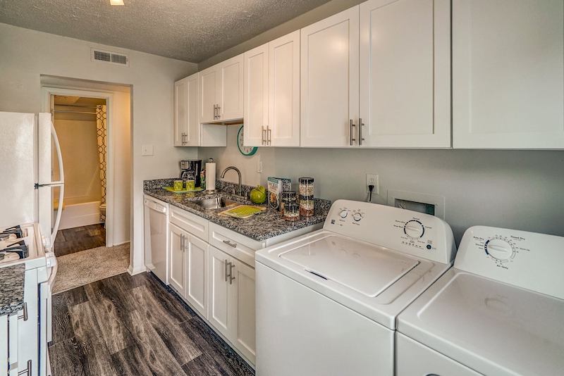 Kitchen with white cabinets, granite countertops, and a washer and dryer